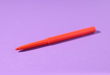 Photo of One twist up eye pencil on purple background, closeup