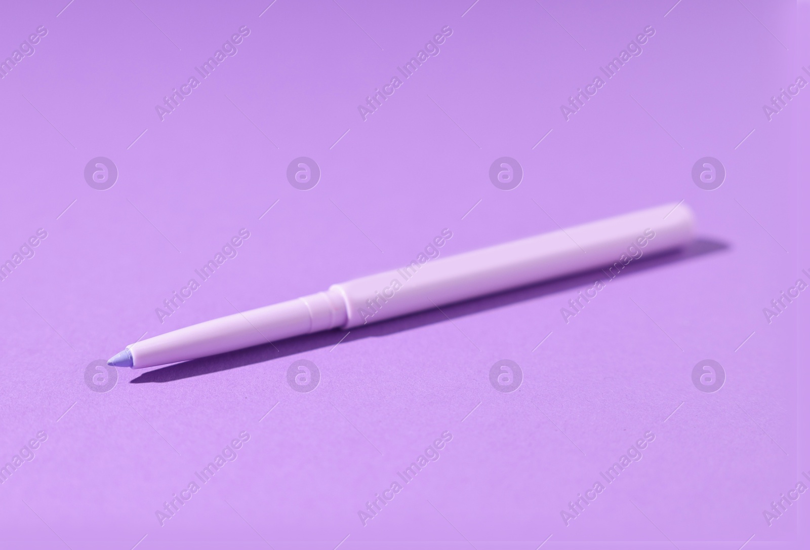One twist up eye pencil on purple background, closeup Photo of One twist up eye pencil on purple background, closeup
