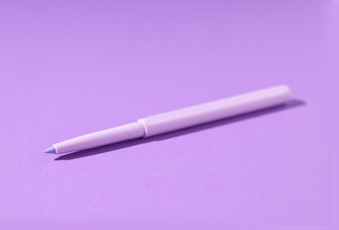 Photo of One twist up eye pencil on purple background, closeup