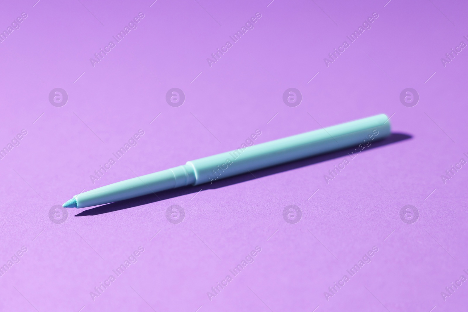 One twist up eye pencil on purple background, closeup Photo of One twist up eye pencil on purple background, closeup