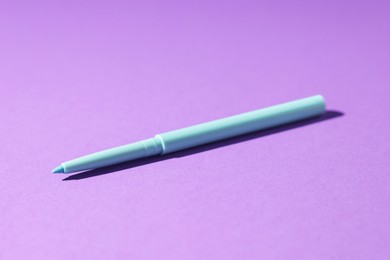 Photo of One twist up eye pencil on purple background, closeup