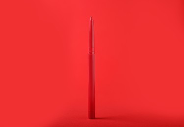 Photo of One twist up eye pencil on red background, closeup