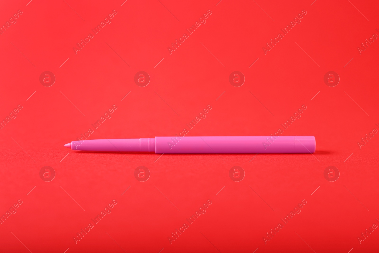 One twist up eye pencil on red background, closeup Photo of One twist up eye pencil on red background, closeup