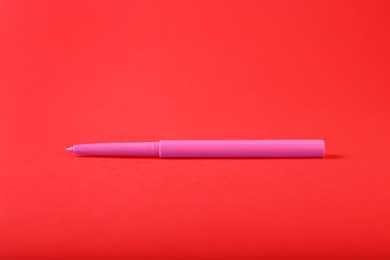 Photo of One twist up eye pencil on red background, closeup