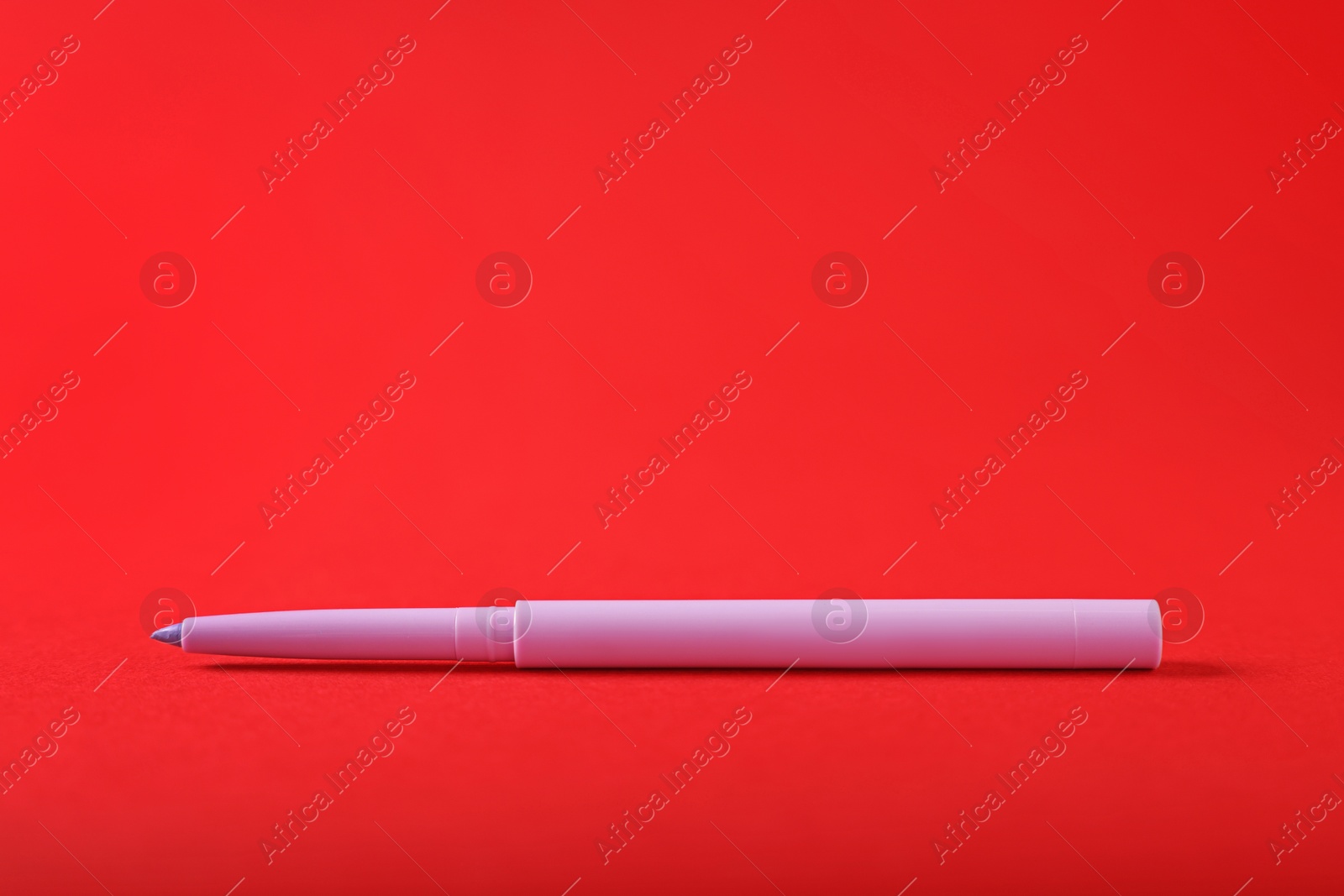 One twist up eye pencil on red background, closeup Photo of One twist up eye pencil on red background, closeup