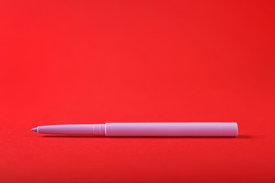 Photo of One twist up eye pencil on red background, closeup