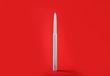 Photo of One twist up eye pencil on red background, closeup