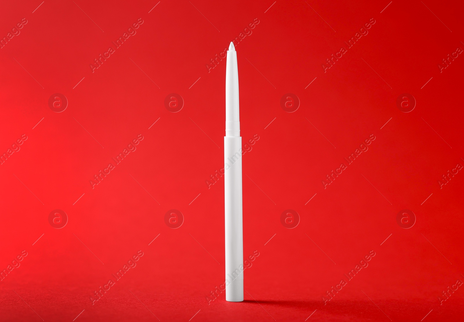 One twist up eye pencil on red background, closeup Photo of One twist up eye pencil on red background, closeup