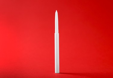 Photo of One twist up eye pencil on red background, closeup