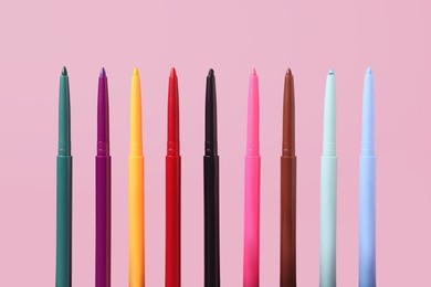 Photo of Colorful twist up eye pencils on pink background, closeup