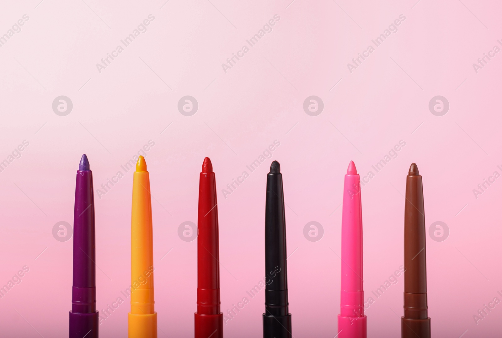 Colorful twist up eye pencils on pink background, closeup Photo of Colorful twist up eye pencils on pink background, closeup