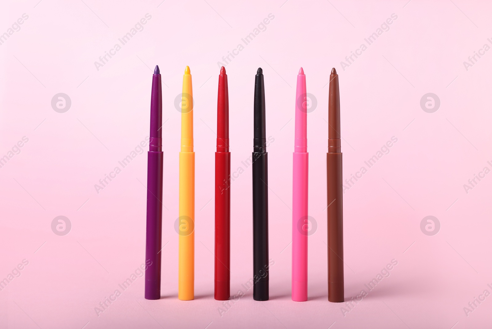 Colorful twist up eye pencils on pink background, closeup Photo of Colorful twist up eye pencils on pink background, closeup