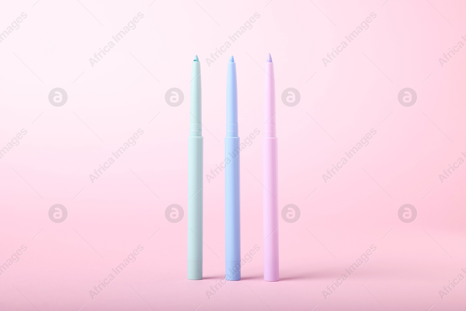 Colorful twist up eye pencils on pink background, closeup Photo of Colorful twist up eye pencils on pink background, closeup