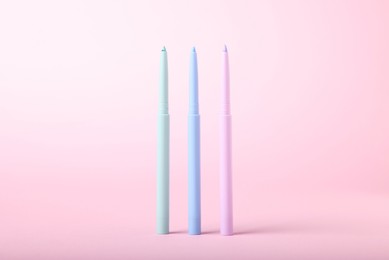 Photo of Colorful twist up eye pencils on pink background, closeup
