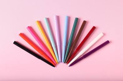 Photo of Colorful twist up eye pencils on pink background, flat lay