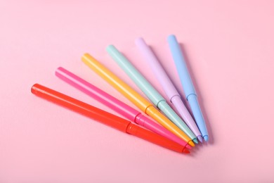 Photo of Colorful twist up eye pencils on pink background, closeup