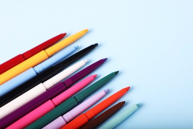 Photo of Colorful twist up eye pencils on light blue background. Space for text