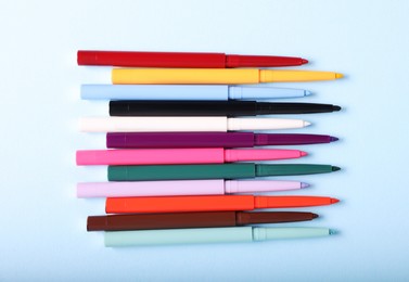Photo of Colorful twist up eye pencils on light blue background, flat lay