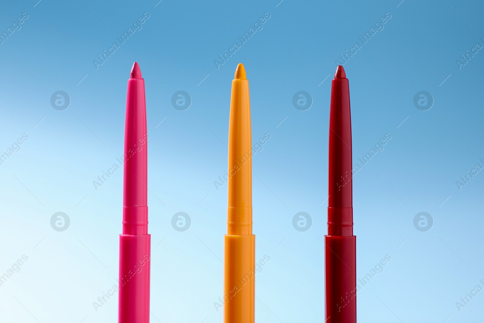 Colorful twist up eye pencils on light blue gradient background, closeup Photo of Colorful twist up eye pencils on light blue gradient background, closeup