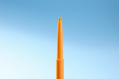 Photo of One twist up eye pencil on light blue gradient background, closeup