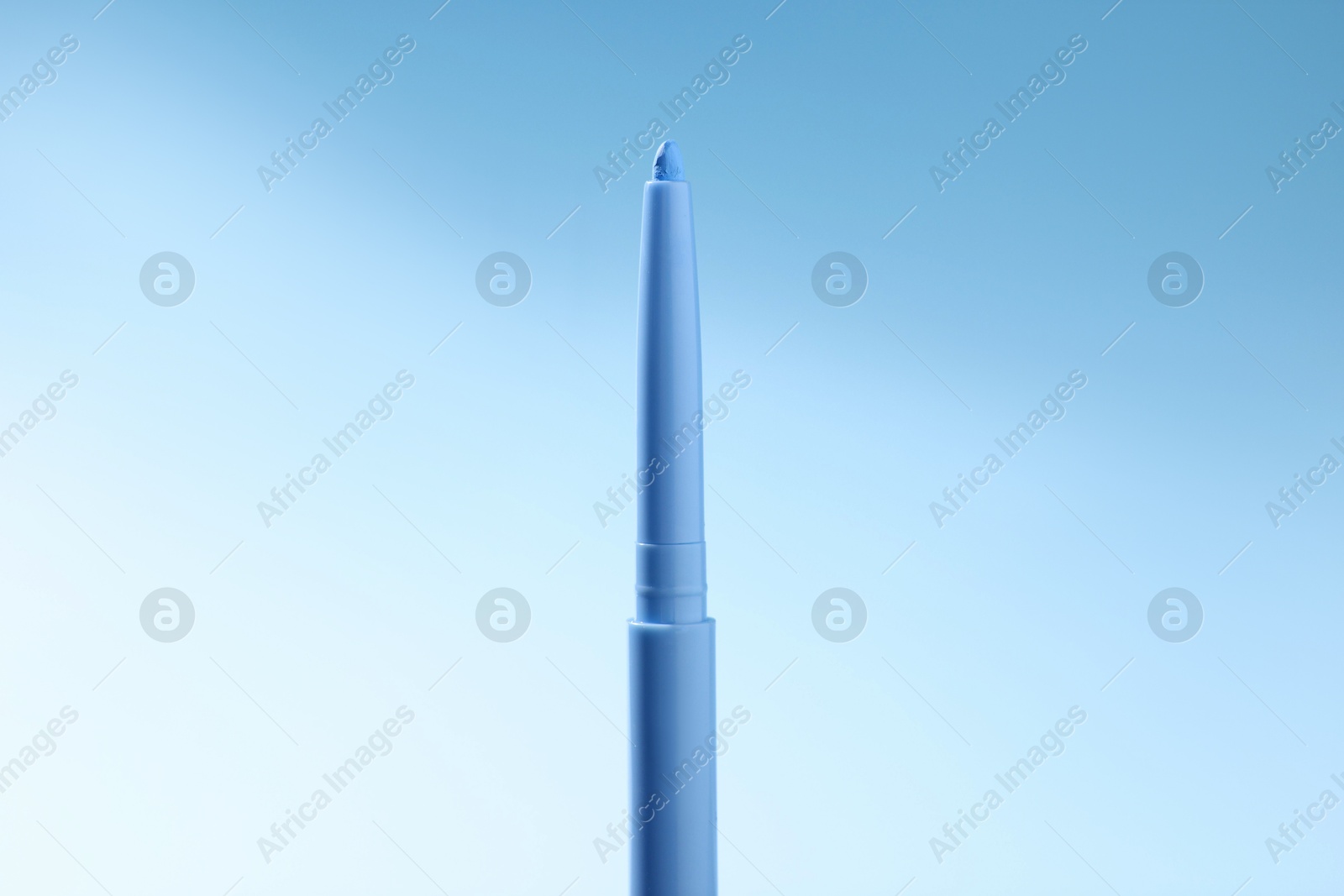 One twist up eye pencil on light blue gradient background, closeup Photo of One twist up eye pencil on light blue gradient background, closeup