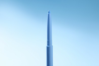 Photo of One twist up eye pencil on light blue gradient background, closeup
