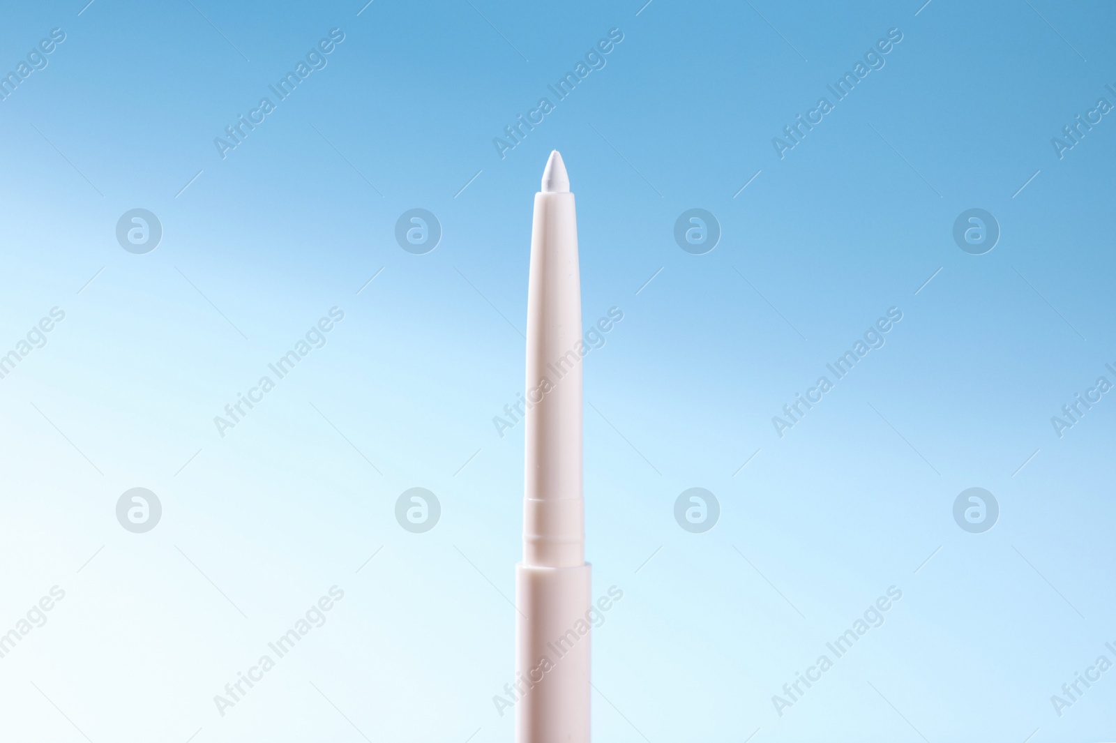 One twist up eye pencil on light blue gradient background, closeup Photo of One twist up eye pencil on light blue gradient background, closeup