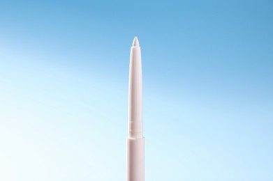 Photo of One twist up eye pencil on light blue gradient background, closeup