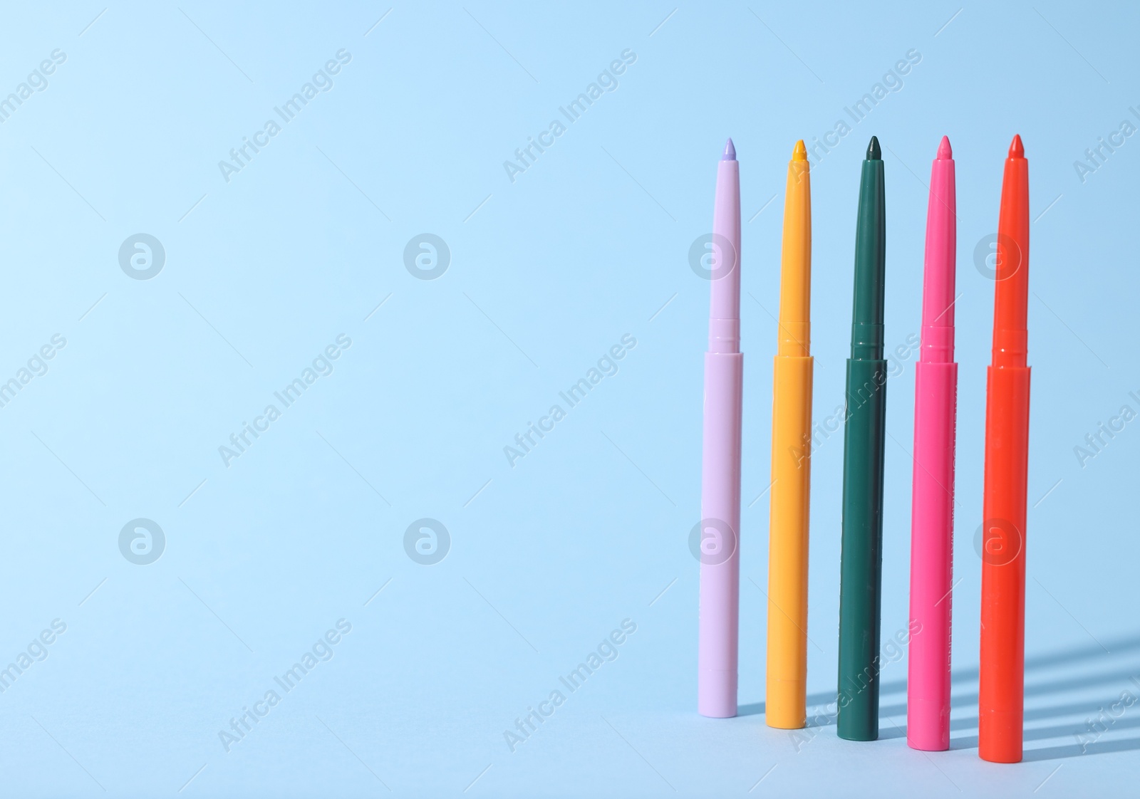 Colorful twist up eye pencils on light blue background. Space for text Photo of Colorful twist up eye pencils on light blue background. Space for text