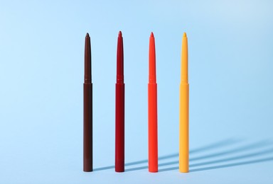 Photo of Colorful twist up eye pencils on light blue background