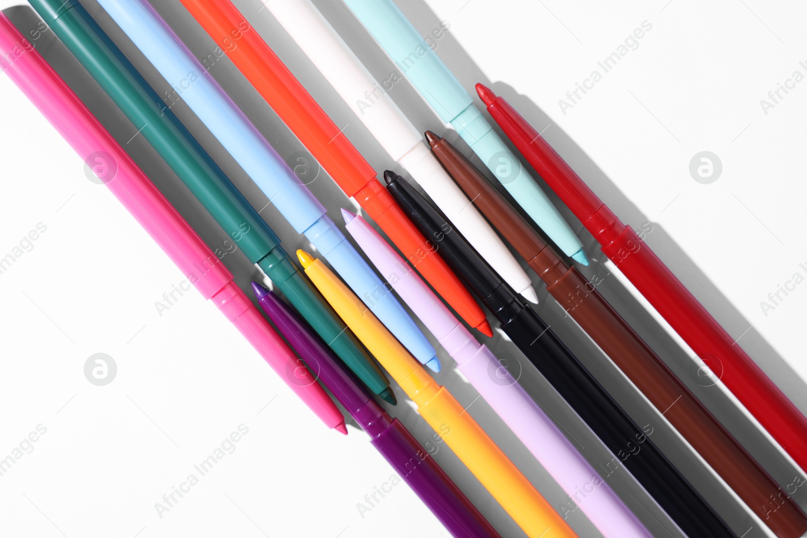 Colorful twist up eye pencils on white background, flat lay Photo of Colorful twist up eye pencils on white background, flat lay