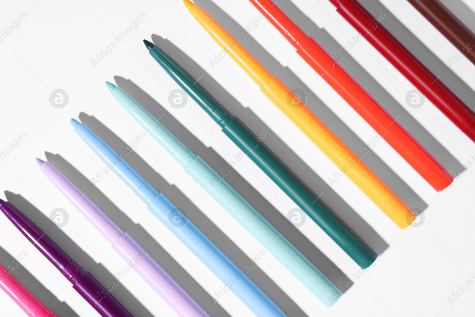 Colorful twist up eye pencils on white background, flat lay Photo of Colorful twist up eye pencils on white background, flat lay