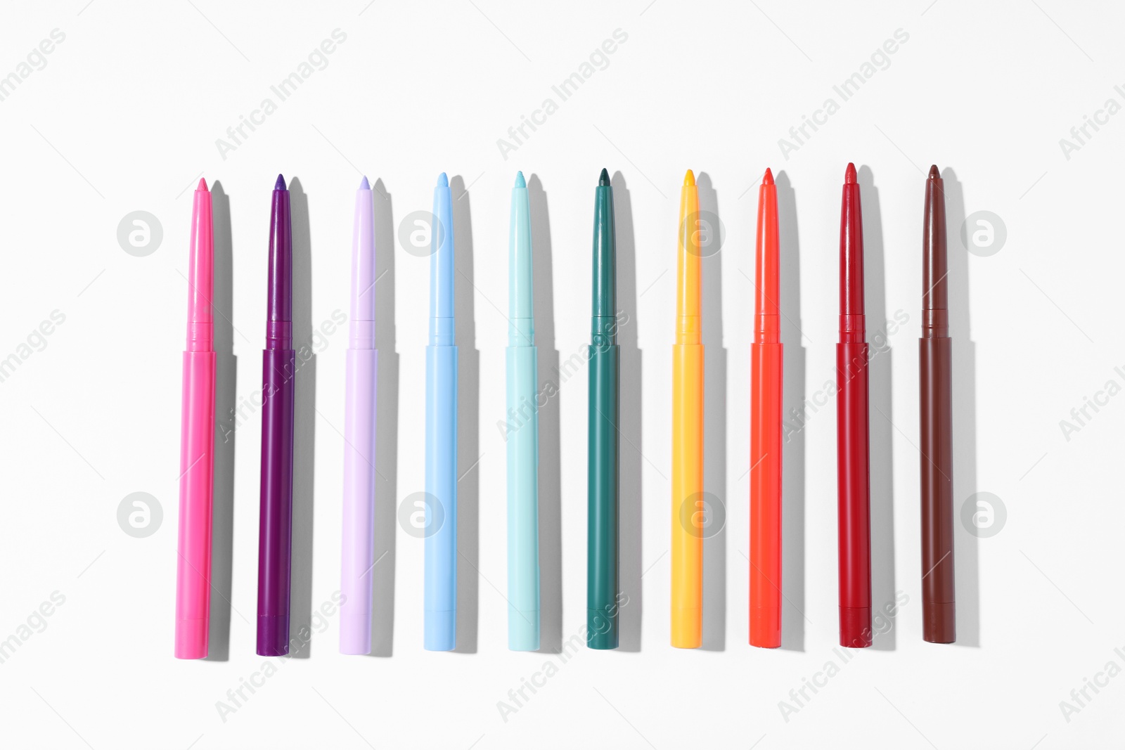 Colorful twist up eye pencils on white background, flat lay Photo of Colorful twist up eye pencils on white background, flat lay