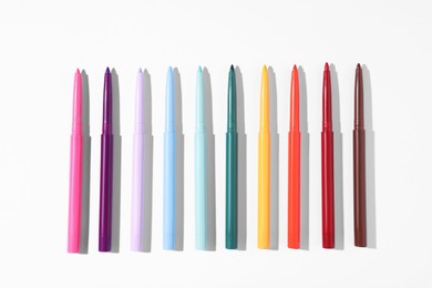 Photo of Colorful twist up eye pencils on white background, flat lay
