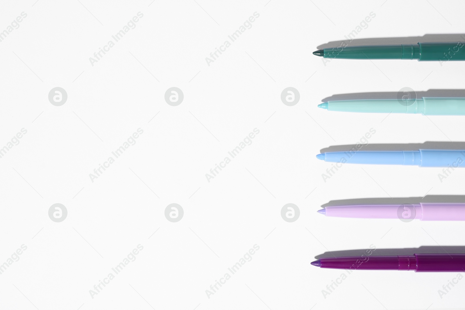Colorful twist up eye pencils on white background, flat lay. Space for text Photo of Colorful twist up eye pencils on white background, flat lay. Space for text