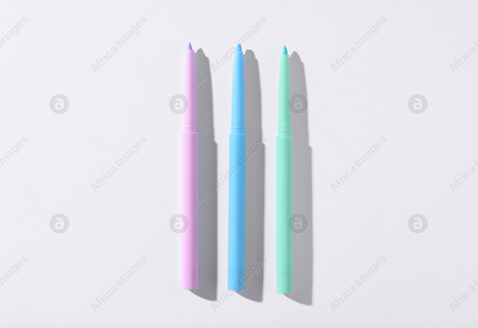 Colorful twist up eye pencils on white background, flat lay Photo of Colorful twist up eye pencils on white background, flat lay