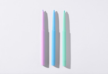 Photo of Colorful twist up eye pencils on white background, flat lay