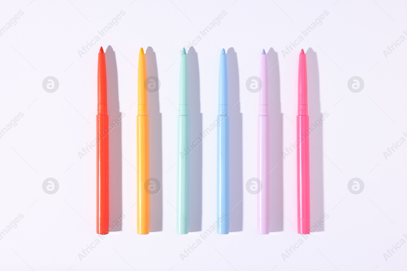 Colorful twist up eye pencils on white background, flat lay Photo of Colorful twist up eye pencils on white background, flat lay