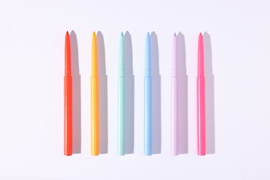 Photo of Colorful twist up eye pencils on white background, flat lay