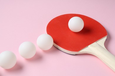 Photo of Ping pong racket and balls on pink background, closeup