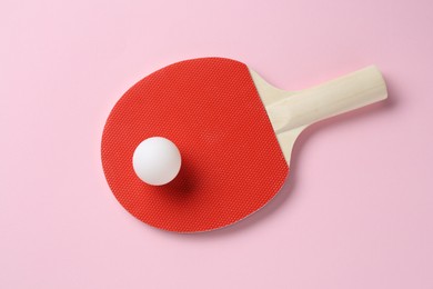 Photo of Ping pong racket and ball on pink background, top view