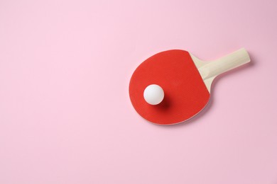 Photo of Ping pong racket and ball on pink background, top view. Space for text