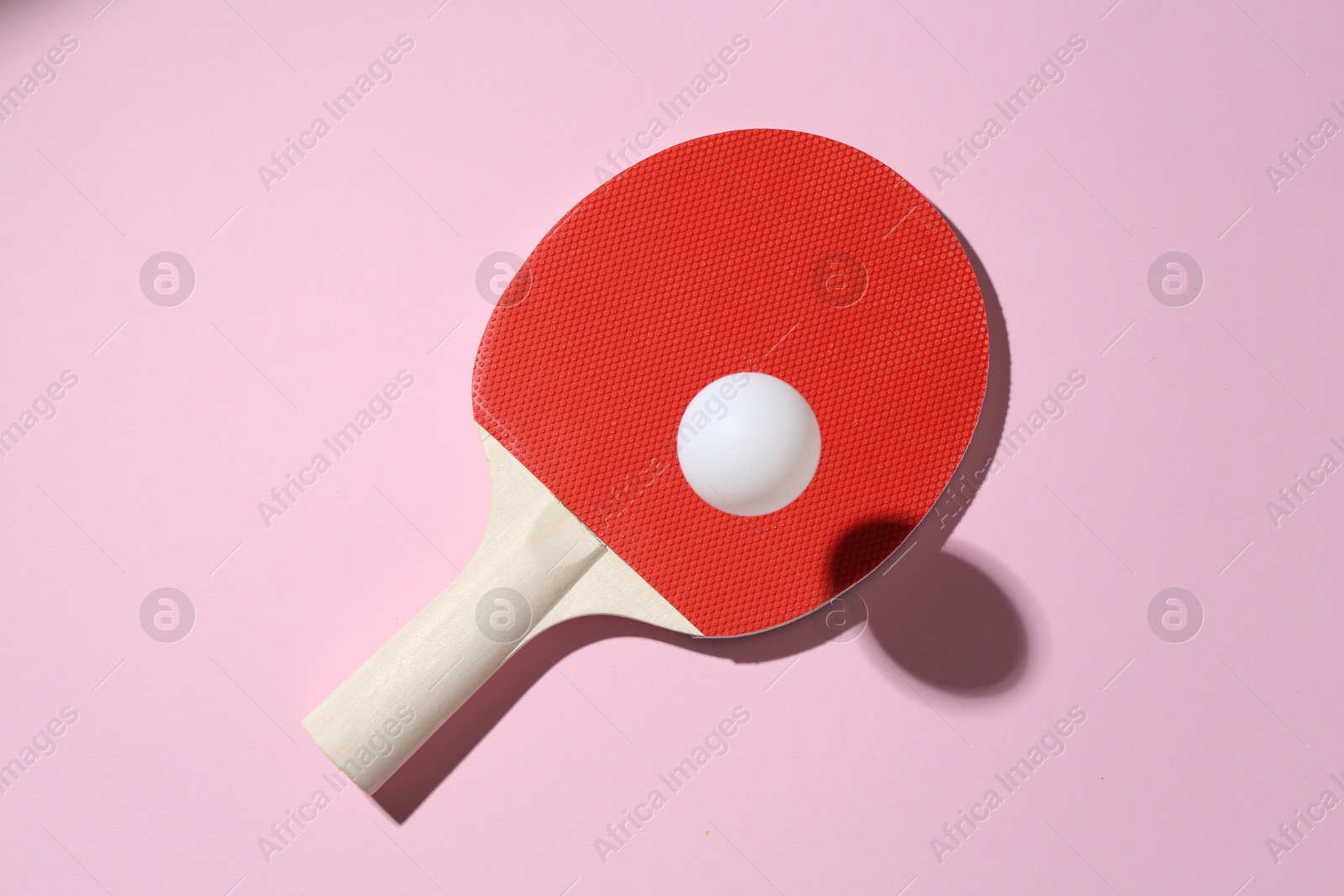 Ping pong racket and ball on pink background, top view Photo of Ping pong racket and ball on pink background, top view