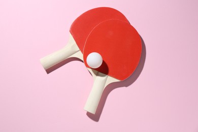 Photo of Ping pong rackets and ball on pink background, flat lay