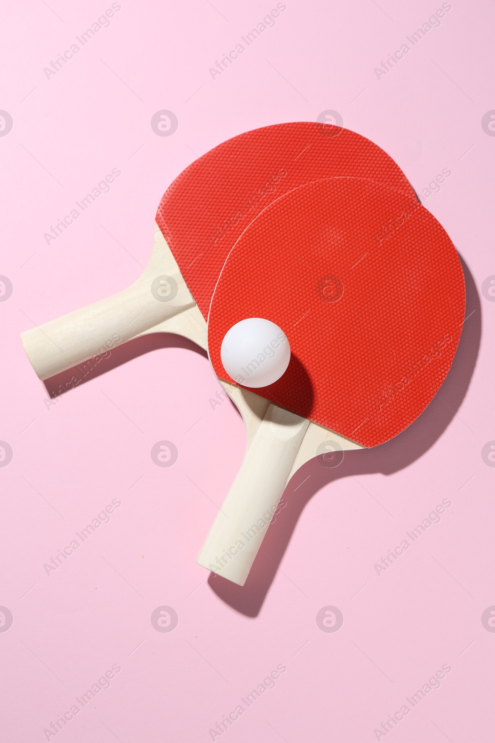 Ping pong rackets and ball on pink background, flat lay Photo of Ping pong rackets and ball on pink background, flat lay