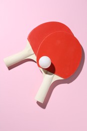 Photo of Ping pong rackets and ball on pink background, flat lay