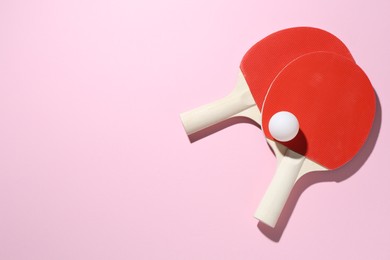 Photo of Ping pong rackets and ball on pink background, flat lay. Space for text
