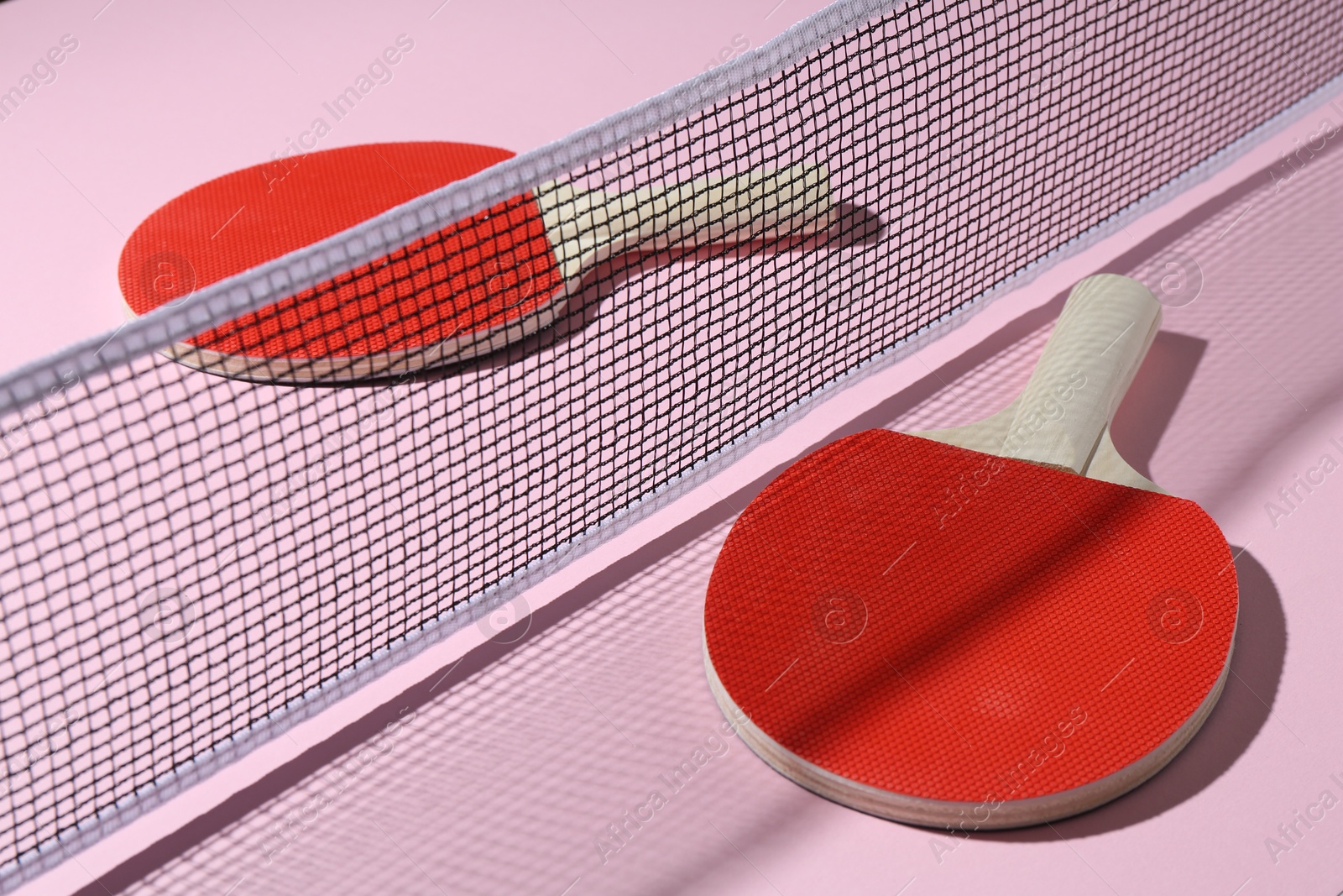 Ping pong rackets and net on pink background, closeup Photo of Ping pong rackets and net on pink background, closeup