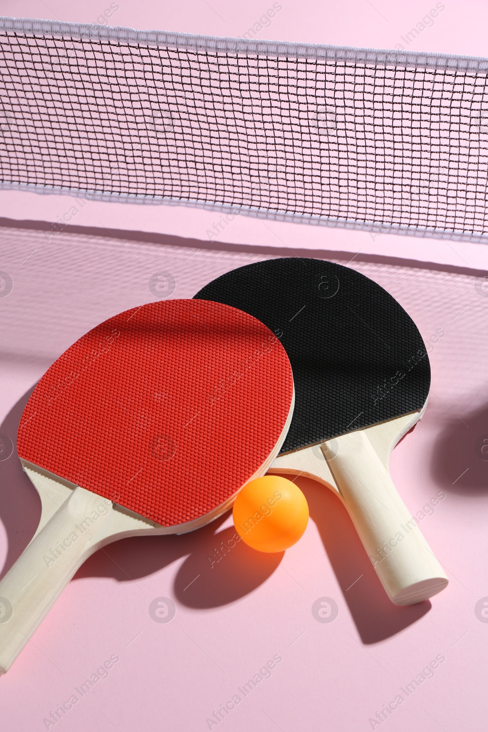 Ping pong rackets, ball and net on pink background, above view Photo of Ping pong rackets, ball and net on pink background, above view