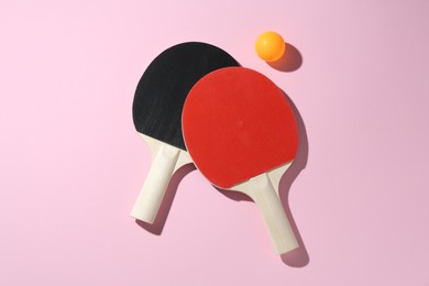 Photo of Ping pong rackets and ball on pink background, flat lay